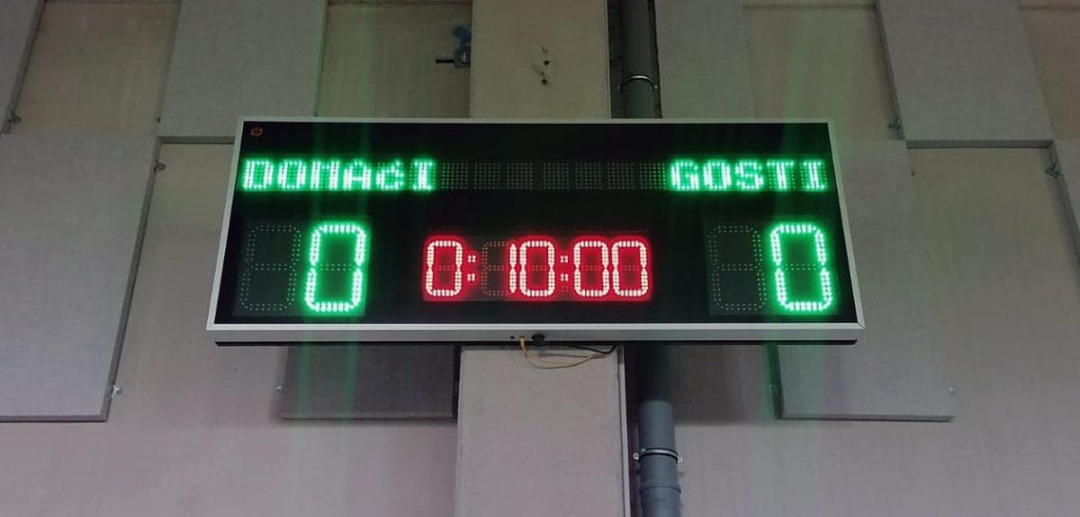 Semafor montiran visoko na zidu sportske dvorane s golom i košem u pozadini