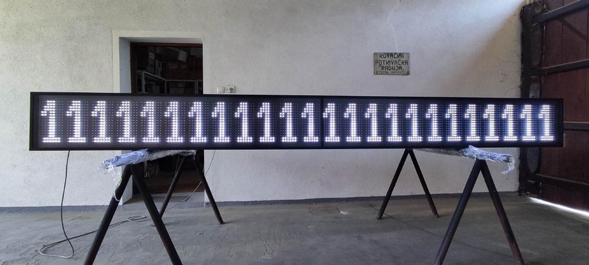 LED display panel s nizom brojki, snimljen frontalno u radioničkom prostoru
